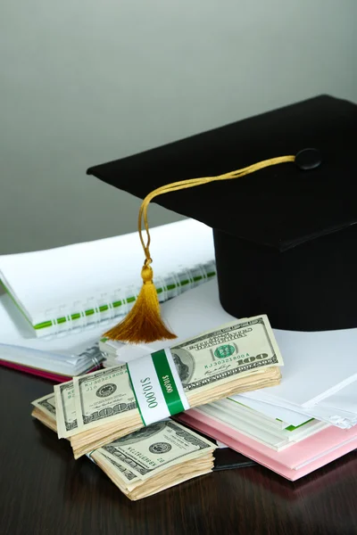 Dinero para graduación o entrenamiento en mesa de madera sobre fondo gris —  Fotos de Stock