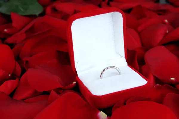 Anillo rodeado de pétalos de rosa sobre mesa de madera —  Fotos de Stock