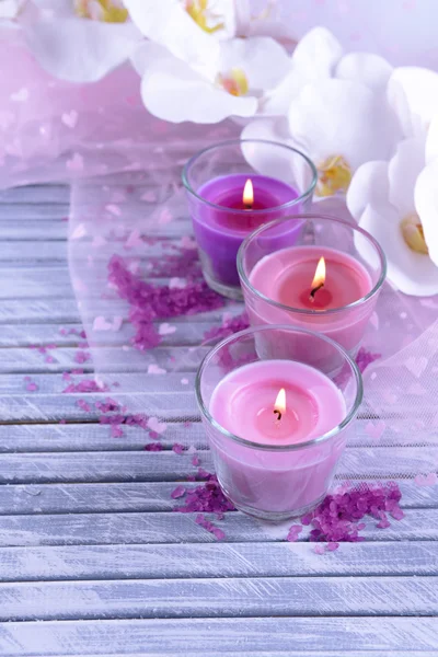 Hermosas velas de colores y flores de orquídea, sobre fondo de madera de color — Foto de Stock