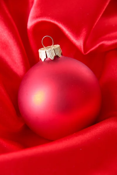Beautiful Christmas ball on red satin cloth — Stock Photo, Image