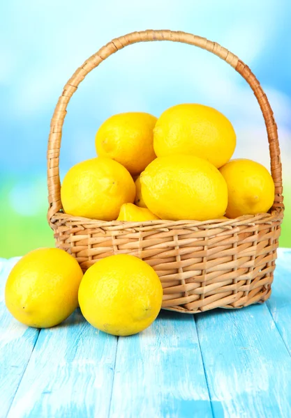 Limones maduros en canasta de mimbre sobre mesa sobre fondo brillante —  Fotos de Stock