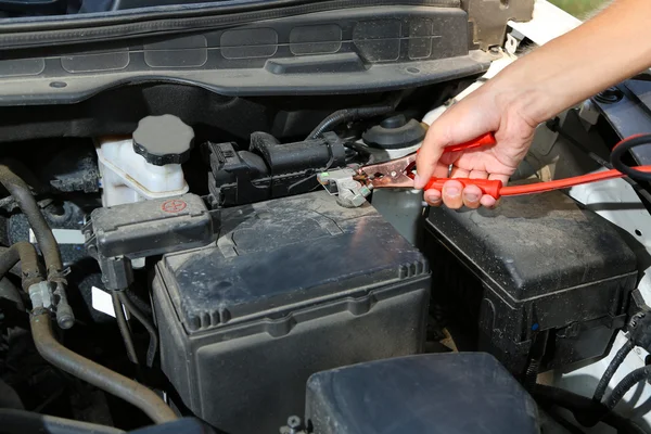 Automechaniker nutzt Batterieüberbrückungskabel, um tote Batterie aufzuladen — Stockfoto