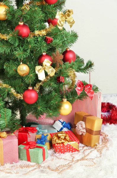 Dekorerad julgran med gåvor på grå vägg bakgrund — Stockfoto