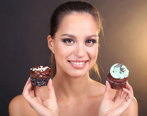 Retrato de hermosa joven con cupcake de chocolate sobre fondo marrón — Foto de Stock