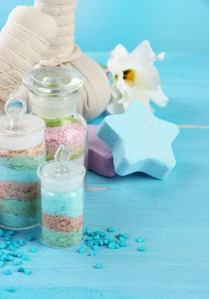 Aromatické soli ve skleněných lahvích a bylinné komprimovat koule pro lázeňské léčby, na modrém pozadí — Stock fotografie