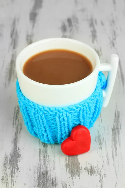 Cup with knitted thing on it on wooden table close up — Stock Photo, Image