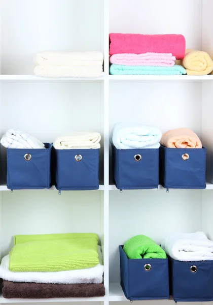 Blue textile boxes with towels in white shelves — Stock Photo, Image