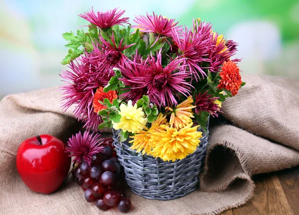 Hasır vazo ve meyve parlak zemin üzerine güzel çiçekler ile kompozisyon — Stok fotoğraf