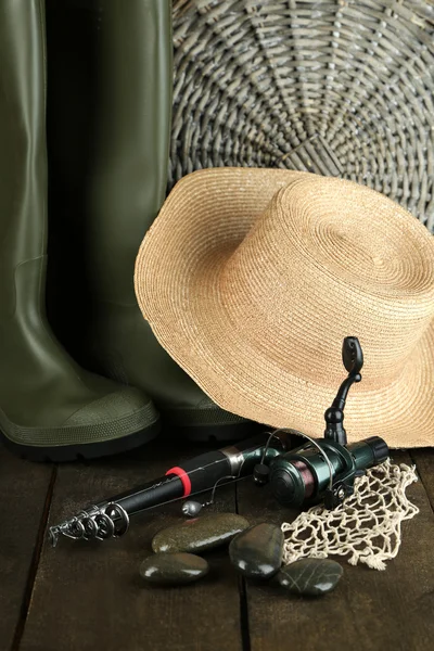 Fishing rod, gumboots and hat on wooden table close-up — Stock Photo, Image