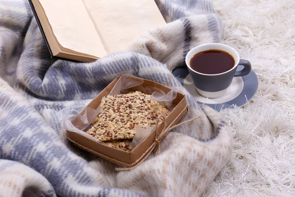 Composition with warm plaid, book, cup of hot drink on color carpet background — Stock Photo, Image