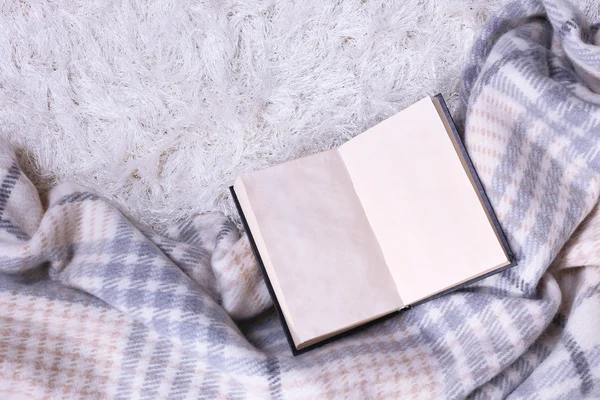 Composition with warm plaid, book, on color carpet background — Stock Photo, Image