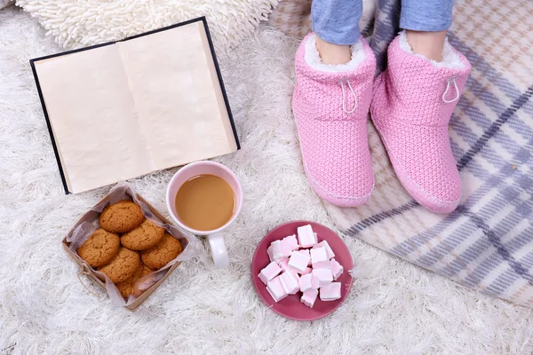 Composición con cuadros calientes, libro, taza de bebida caliente y piernas femeninas, sobre fondo de alfombra de color — Foto de Stock