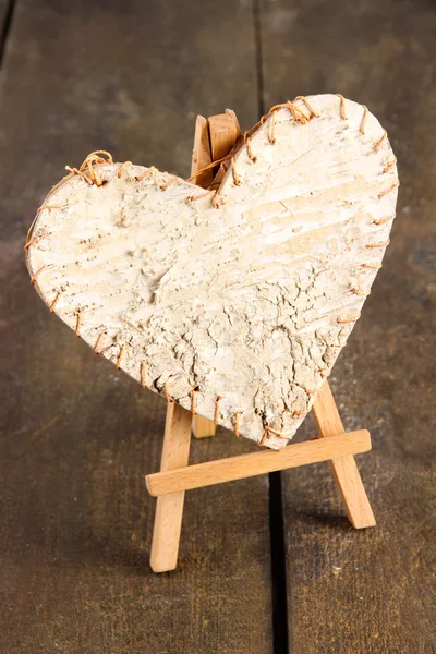 Coração decorativo no cavalete, no fundo de madeira — Fotografia de Stock