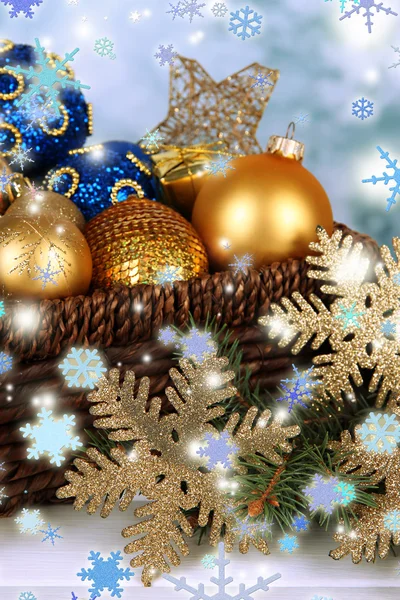 Рождественские украшения в корзине и ели ветви на столе на ярком фоне — стоковое фото