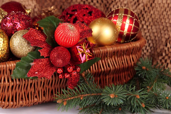 Christmas decorations in basket and spruce branches on table on brown background — Stock Photo, Image