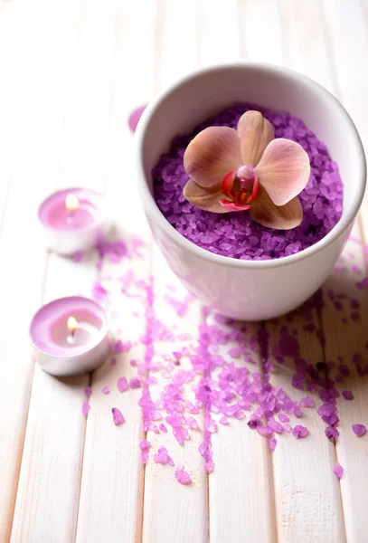 Still life with beautiful blooming orchid flower, towel and bowl with sea salt, on color wooden background — Stock Photo, Image