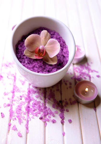 Still life with beautiful blooming orchid flower, towel and bowl with sea salt, on color wooden background — Stock Photo, Image