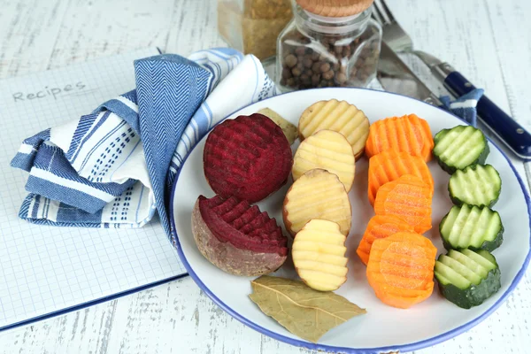 Beautiful sliced vegetables, on plate, on wooden background — Stock Photo, Image