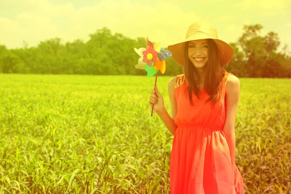 Portrait of beautiful young woman with pinwheel in the field — Stock Photo, Image