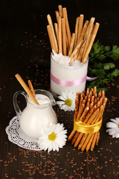 Tasty crispy sticks with pitcher and glass with sour cream on wooden table close-up — Stock Photo, Image