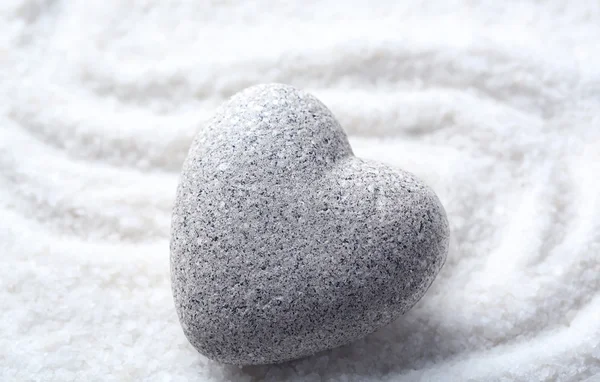 Grey zen stone in shape of heart, on sand background — Stockfoto