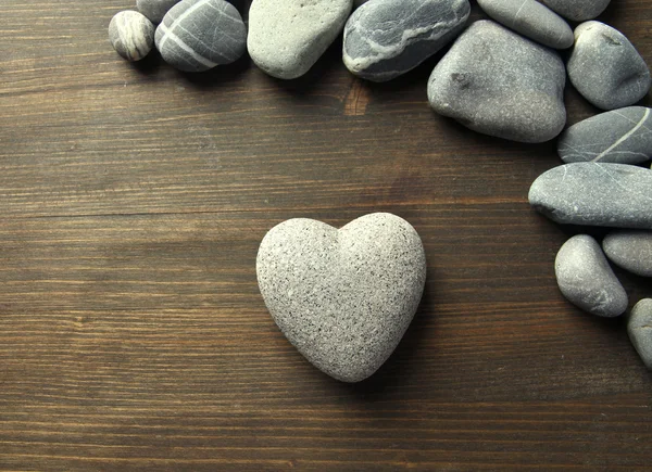 Piedra gris en forma de corazón, sobre fondo de madera —  Fotos de Stock