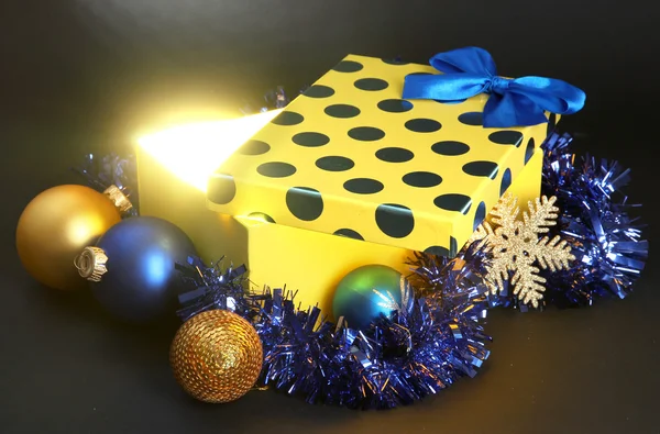 Gift box with bright light on it on dark grey background — Stock Photo, Image