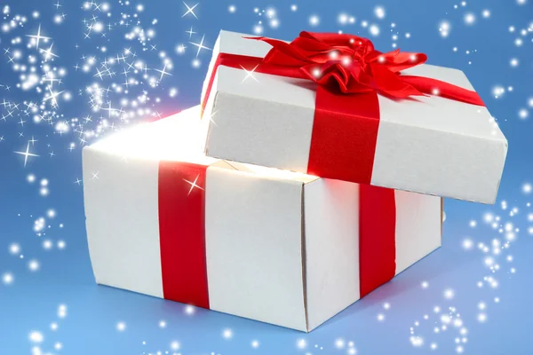 Caja de regalo con luz brillante sobre fondo azul —  Fotos de Stock