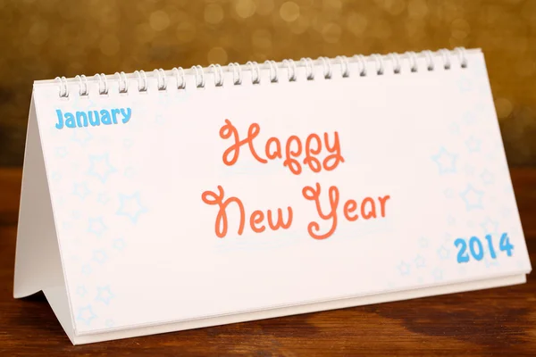 New Year calendar on wooden table, on shiny golden background — Stock Photo, Image