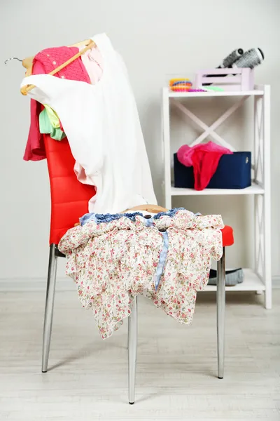 Heap of clothes on color chair, on gray background — Stock Photo, Image