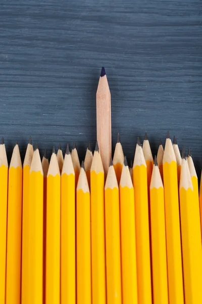 Εορταστικό μολύβι μεταξύ συνηθισμένο μολύβια, σε φόντο χρώμα — Φωτογραφία Αρχείου