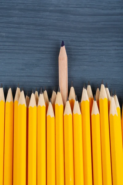 Celebratory pencil among usual pencils, on color background — Stock Photo, Image