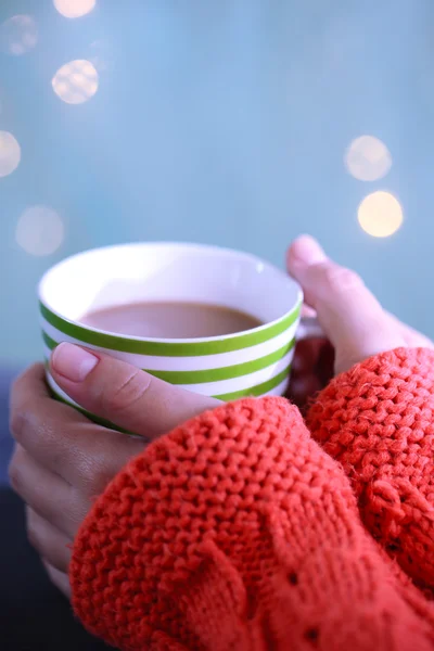 Handen met mok hete drinken, close-up, op lichte achtergrond — Stockfoto