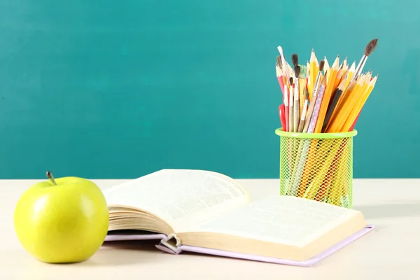 Schulbedarf auf Tisch auf Tafel-Hintergrund — Stockfoto