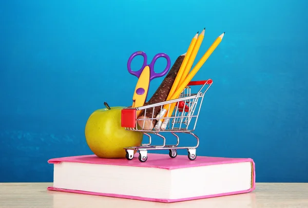 stock image School supplies in supermarket cart on blackboard background