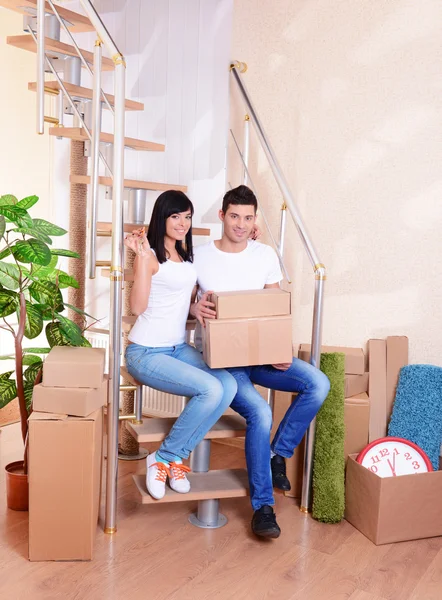 Young couple with boxes in new home on staircase background — Stock Photo, Image