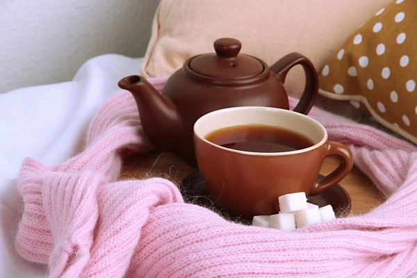 Copo e bule com cachecol na cama de perto — Fotografia de Stock