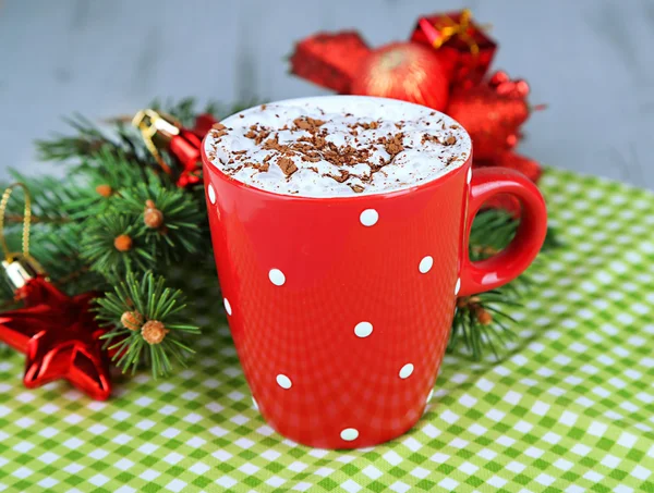 Chocolat chaud avec crème dans la tasse de couleur, sur la serviette, sur fond décorations de Noël — Photo