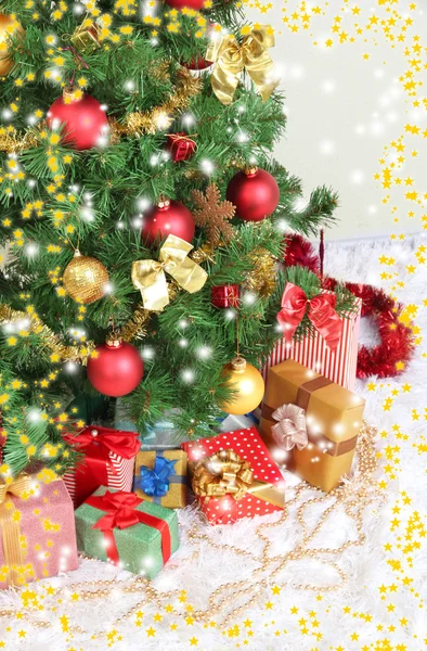 Decorated Christmas tree with gifts on grey wall background — Stock Photo, Image