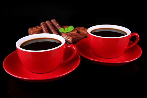 Copos vermelhos de café forte e barras de chocolate isoladas em preto — Fotografia de Stock