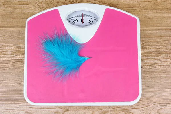 Feather on scales on table close-up — Stock Photo, Image