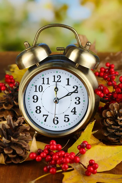 Vieille horloge sur feuilles d'automne sur table en bois sur fond naturel — Photo