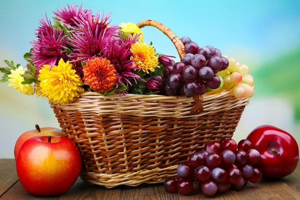 Hasır sepet ve meyve parlak zemin üzerine güzel çiçekler ile kompozisyon — Stok fotoğraf