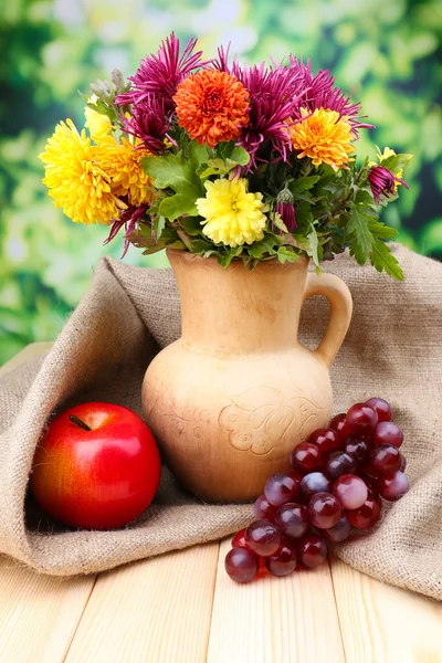 Gyönyörű virágok, kancsó, és a gyümölcsök, a fényes háttérben összetétele — Stock Fotó