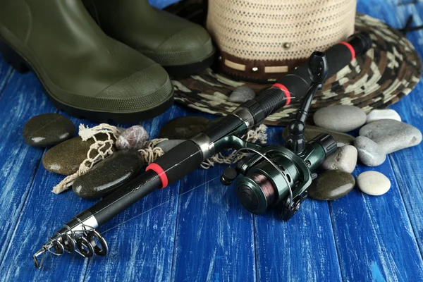 Fishing rod, gumboots and hat on wooden table close-up — Stock Photo, Image