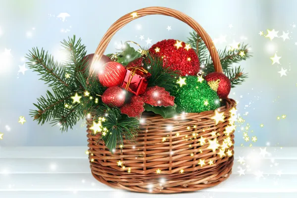 Christmas decorations in basket and spruce branches on table on bright background — Stock Photo, Image