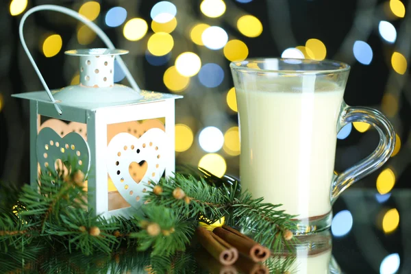 Tasse Eierlikör mit Tannenzweigen und Laterne auf Tisch auf hellem Hintergrund — Stockfoto