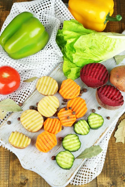 Belos legumes fatiados, na tábua de corte, no fundo de cor — Fotografia de Stock