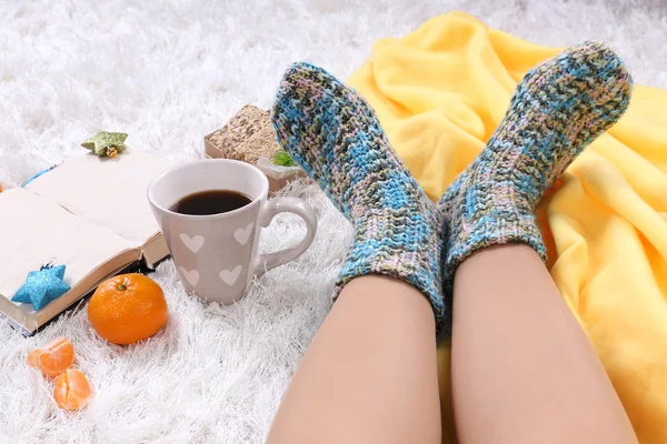 Composizione con plaid caldo, libro, k e gambe femminili, su sfondo tappeto di colore — Foto Stock