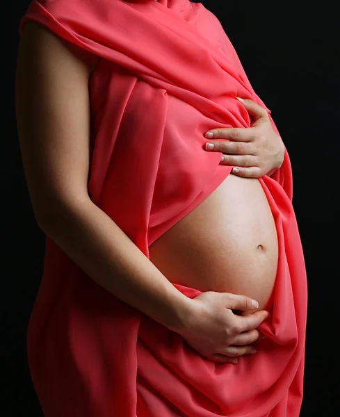 Young pregnant woman with coral material on black background — Stock Photo, Image